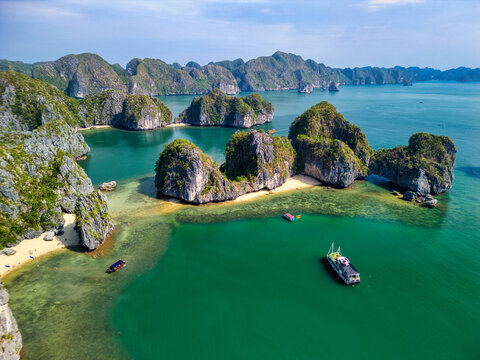 Aerial view of Cat Ba Archipelago with limestone karsts, emerald waters, and small boats near sandy beaches in Ha Tu, Hai Phong, Vietnam.