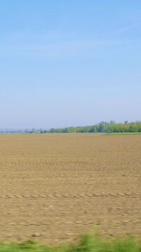 View from car side window of huge empty farm land on a sunny day slow