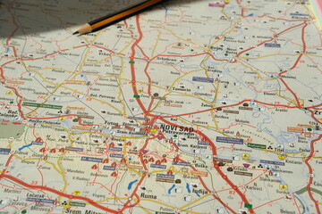 Naklejka premium Map study with pencil over route and roads, planning travel paths for city exploration and geography learning at a desk, focused and curious atmosphere, educational activity