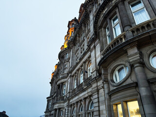 Naklejka premium Historic stone building facade in Edinburgh, Scotland, UK at dusk with ornate Victorian architecture and illuminated windows
