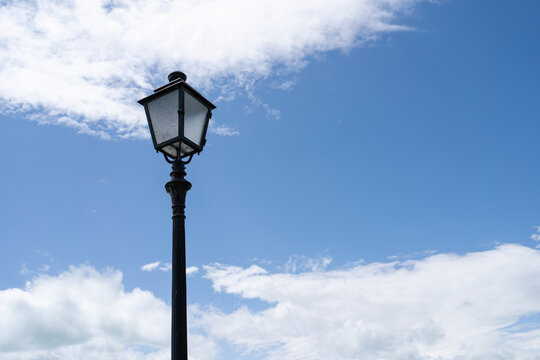 Lamppost pictured over the cloudy blue sky