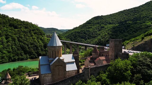 Ancient medieval castle fortress with stone walls and towers on turquoise lake shore aerial view.
