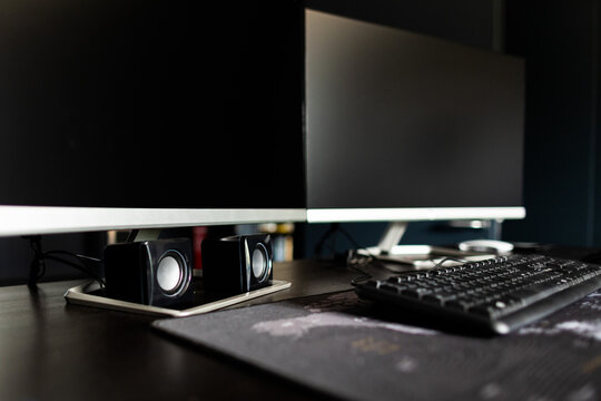 postazione di lavoro in un ufficio con due schermi, una tastiera, un mouse e delle casse audio su una scrivania