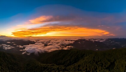 Fototapeta premium Panoramic view of a vibrant sunset over a sea of clouds, with a forested mountain range in the foreground