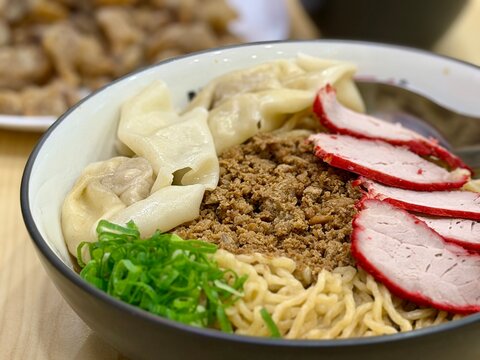 Close up of Indonesian Chinese style pork noodle (bakmi babi) topped with red roasted pork (char siu) and wontons. A savory and comforting dish with rich flavors and textures. 