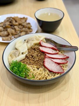 Close up of Indonesian Chinese style pork noodle (bakmi babi) topped with red roasted pork (char siu) and wontons. A savory and comforting dish with rich flavors and textures. 