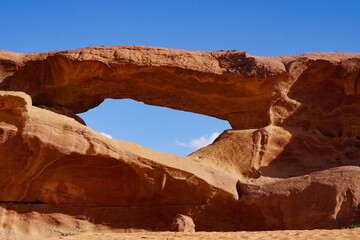 A striking sandstone rock arch in a sunlit desert frames a clear blue sky, symbolizing natural beauty, resilience, and geological time—ideal for travel and nature themes. © Duro Mesiar