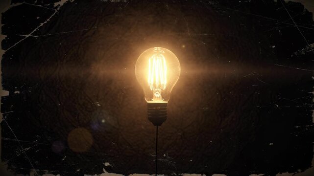 Glowing vintage light bulb with warm glowing filament on dark textured background