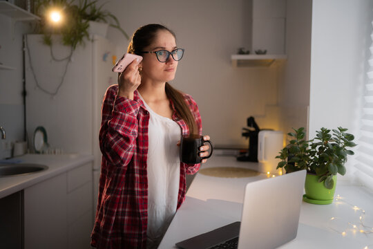 Woman in eyeglasses listen voice message on smartphone using speaker phone listening voicemail at home.