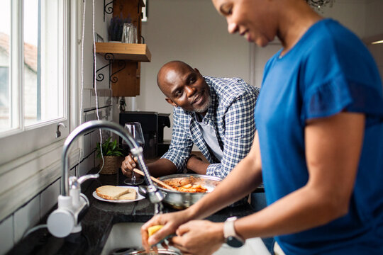Couple talking while washing dishes at home kitchen
