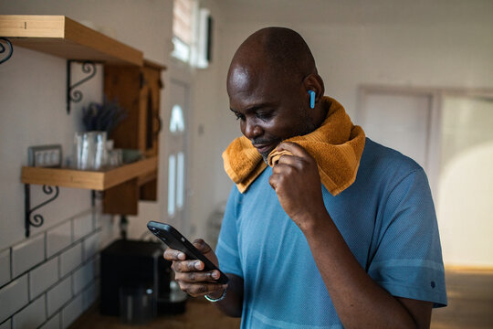 Man checking smartphone after workout in home kitchen