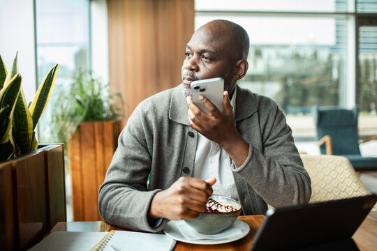 Man using voice assistant on phone in cafe