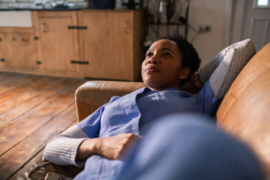 Female nurse resting on sofa at home after shift