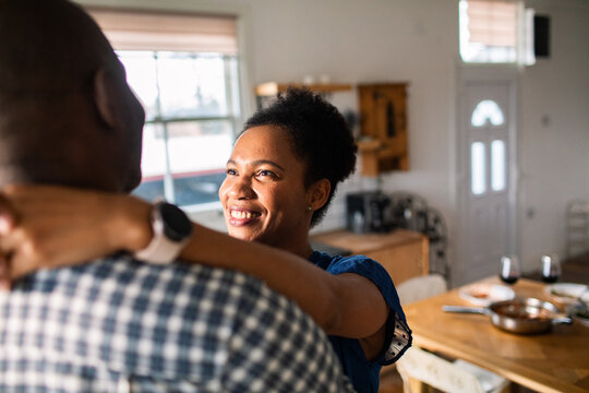 Smiling woman hugging partner in home kitchen