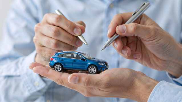 Hands holding toy car with pens