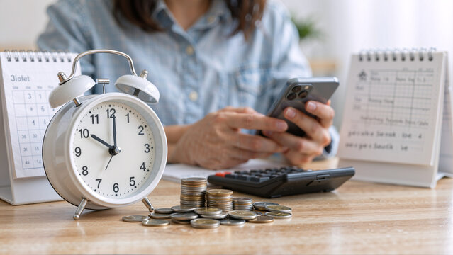Person using phone with alarm clock and coins