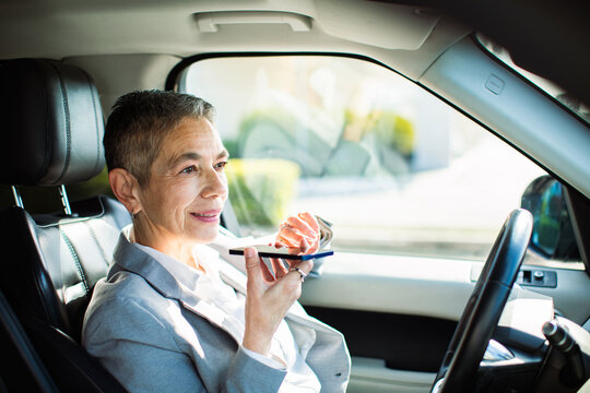 Senior businesswoman using voice assistant in car