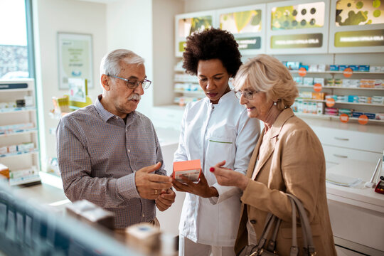 Pharmacist advising senior couple in pharmacy