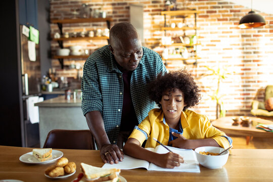 Parent helping child with homework in kitchen