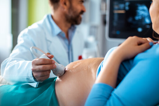 Obstetrician performing prenatal ultrasound on pregnant woman in clinic