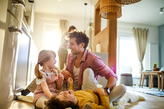 Father playing with kids on kitchen floor at home