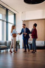 Fototapeta premium Happy embers of human resource team greeting job candidate in office lobby.