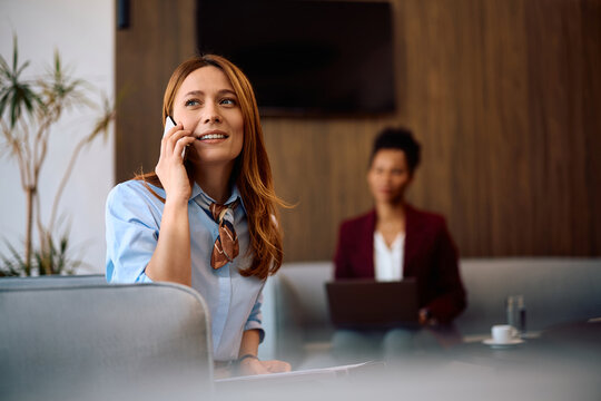 Happy businesswoman talking on smart phone in office.