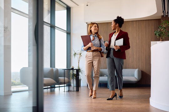 Happy businesswomen talking while working at corporate office.