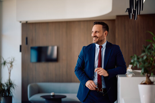 Portrait of happy businessman in office looking away.