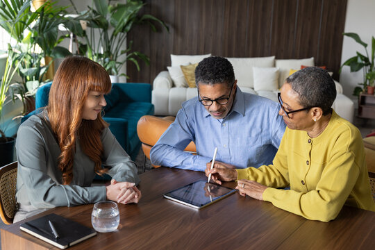 Senior couple signing a digital contract in a meeting