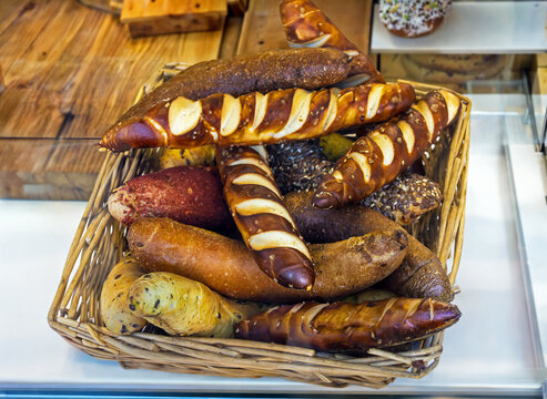 Pile of baked pastry rolls in rattan basket inside bakery interior counter