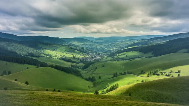 Scenic rolling green hills under a dramatic cloudy sky, revealing a charming valley village below
