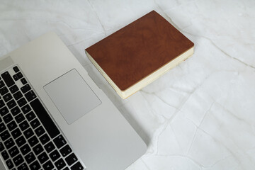 Fototapeta premium Minimal workspace with laptop and notebook on marble desk, representing modern office environment and organization.