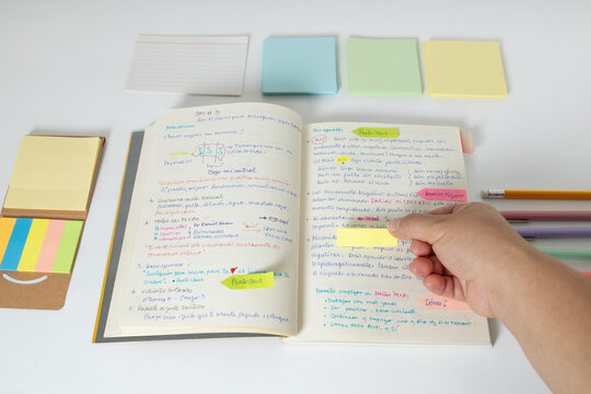Study setup with sticky notes and hand organizing information, highlighting productivity and learning process.