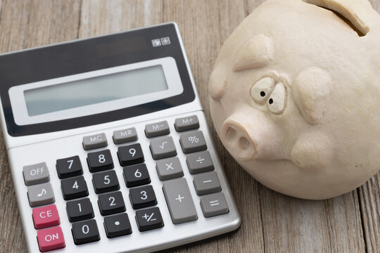 Worried piggy bank with calculator and damage