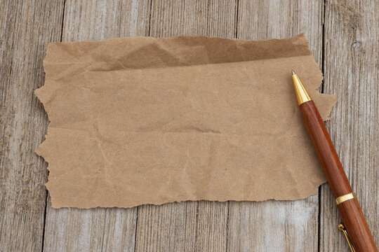 Blank torn kraft paper with pen on wood desk