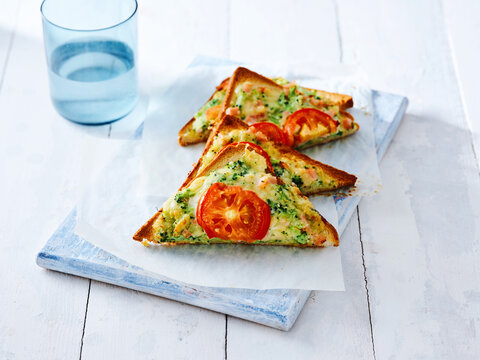 This image showcases a baked vegetable omelet served on toasted bread with fresh tomato slices