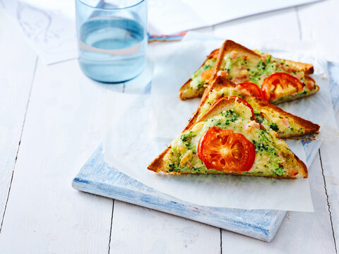 This image showcases a toasted sandwich filled with broccoli and tomato, served with a glass of water. Ideal for promoting healthy lunch choices in cafes, restaurants, and meal prep content