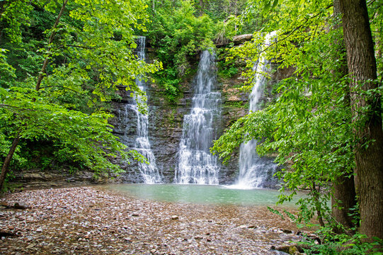 Water flows majestically from the top down the layered cliffs into a pool of cool water. The wet season has provided three amazing streams and lush green foliage. Bokeh.