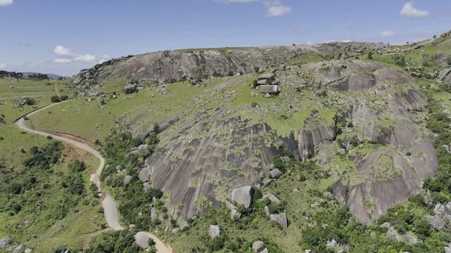 Drone flies up and over hiking trail to the summit and reveals expansive mountainous landscape on a sunny day at Sibebe Rock near Mbabane, Eswatini