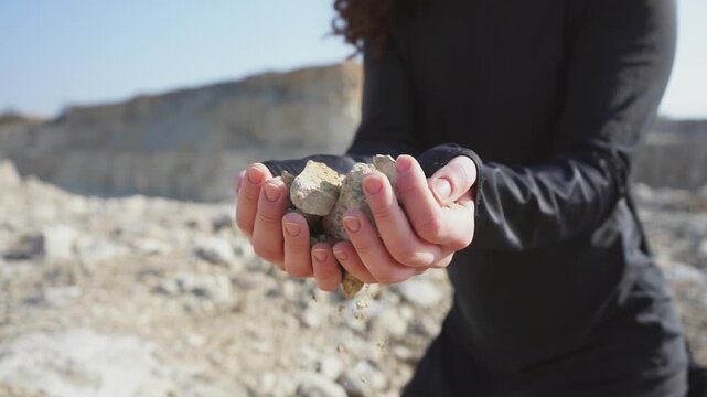 Woman's hands releasing dry earth and crumbling stones