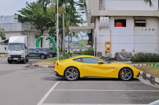 Batam-Indonesia, April 13th 2026:  a yellow Ferrari F12 Berlinetta parked in a modern waterfront area