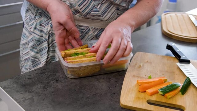 Hands preparing lunchbox with fresh food, healthy meal prep concept