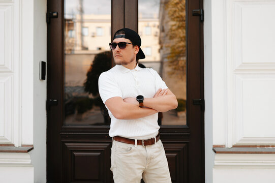 Caucasian Man In White Tshirt, Standing With Arms Crossed In Modern Doorway With Reflective Glass, Confident