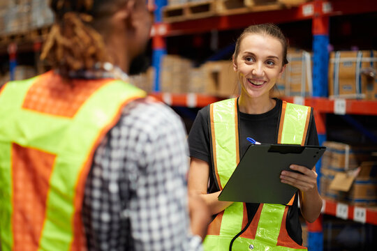 Workers collaborating while reviewing inventory management with each other in a warehouse storage
