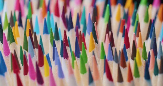 Macro shot of a beautiful pile of sharpened drawing pencils in various bright colors. Detailed pencil tips and wooden texture, perfect for school, art and creativity themes 4K
