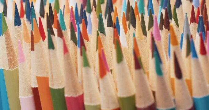 Hypnotic slow motion: sharpened multicolored pencils rotate in a perfect circle. Close-up of pencil leads and wooden bodies, vibrant art supplies concept 4K.