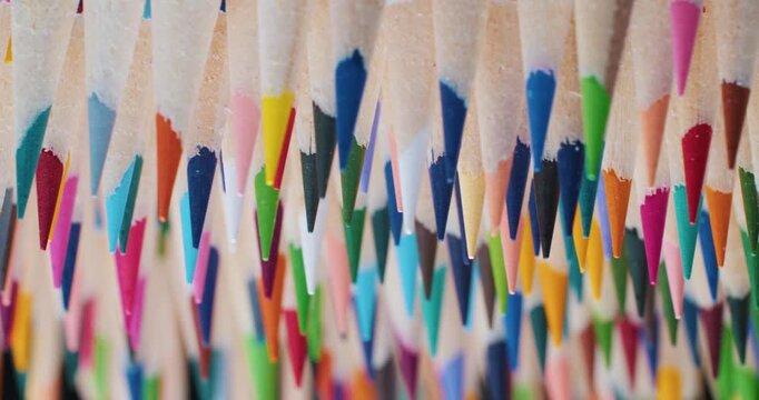 Cinematic slow motion: multicolored sharpened pencils spin smoothly in a circle. Sharp graphite cores and vibrant wood, dynamic artistic stationery footage 4K