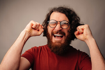 Man Celebrating Victory With Raised Fists And Triumphant Expression, Glasses On, Studio Closeup, Energetic © Vulp