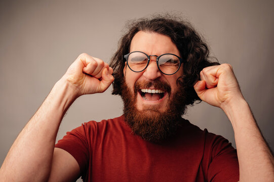 Man Celebrating Victory With Raised Fists And Triumphant Expression, Glasses On, Studio Closeup, Energetic